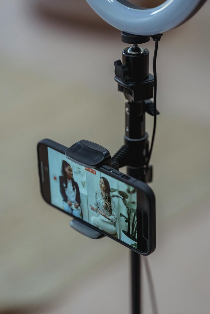Smartphone attached to a stand with a ring light, set up for video recording and live streaming.